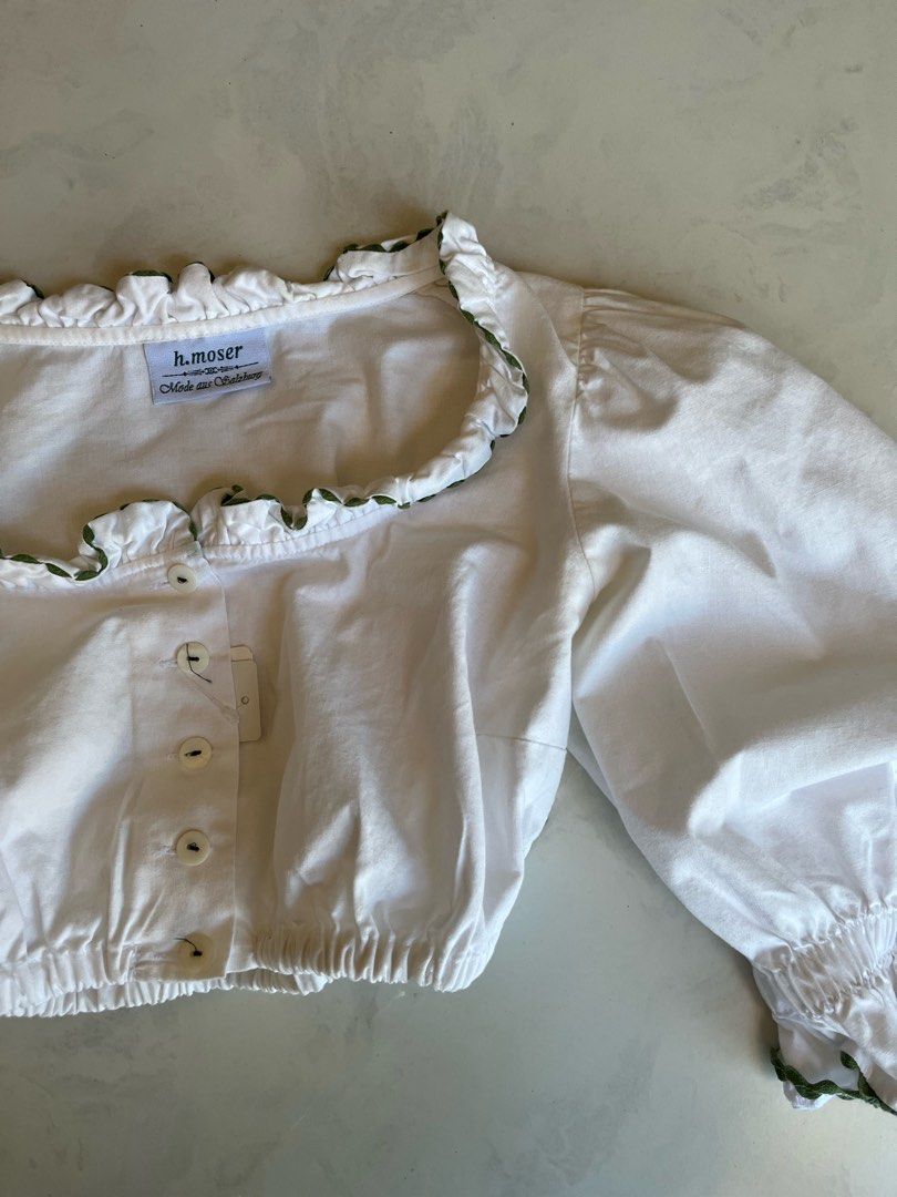 Vintage 100% Pure Cotton Cottagecore Coquette Farmhouse Frilly White Long Sleeve Button Up Wide Neck Crop (Category: Blouses) located in Singapore. Submitted by woodfox (Listing ID 1335160766, Image 3). Description: This gorgeous true vintage European blouse is made out of a 100% soft cotton blend. It features a batwing half sleeve with olive green accents along the hem of the neck and arm. Pair it with a long maxi skirt for the perfect coquette/