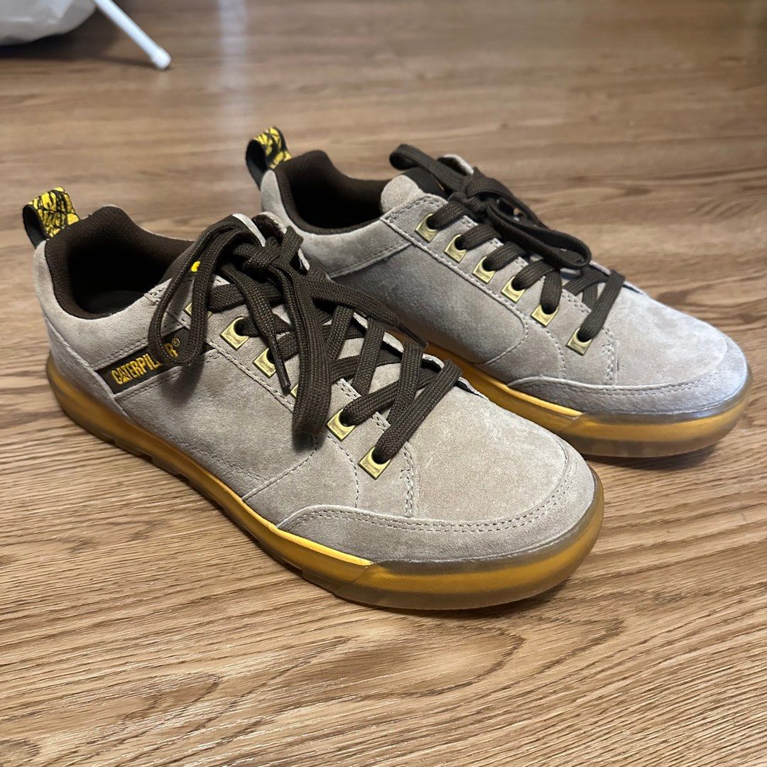 Caterpillar Casual Sneakers Unisex (Category: Sneakers) located in Singapore. Submitted by tequierox (Listing ID 1396379444, Image 4). Description: Lightly used Caterpillar sneakers. Features a grey suede upper with brown laces and a yellow sole. The Caterpillar logo is visible on the insole and side of the shoe. Great for casual wear..