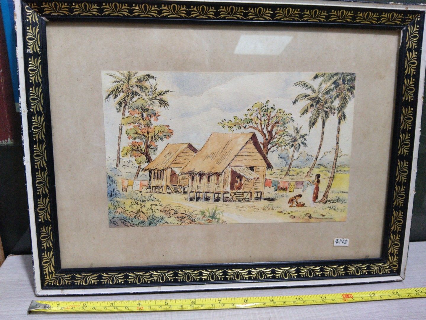1950s Kampong Scenery Watercolour Painting of Tropical Village Scene (Category: Frames & Pictures) located in Singapore. Submitted by mypassionlisbon (Listing ID 1441154919, Image 1). Description: - Framed watercolour painting - kampong scene with stilt houses and palm trees - Figures in foreground - Artist signature: C.H. Soh - Frame: Black and gold decorative border - Dimensions: Approx. 19 inches x 15 inches.