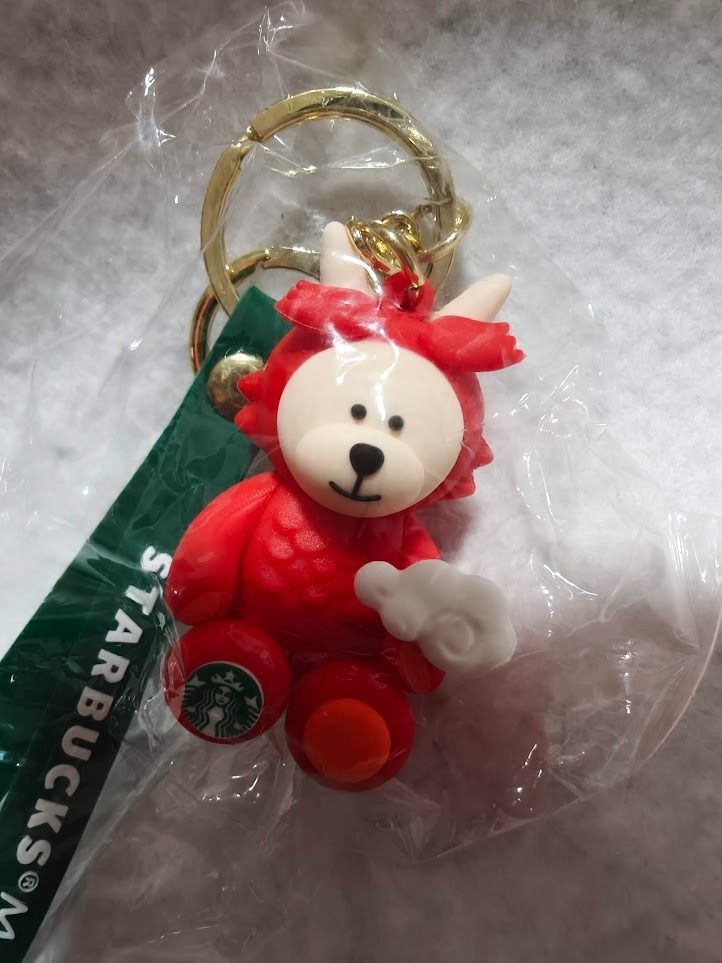 Starbucks Malaysia Year of the Dragon Bearista Keychain (Category: Plushies & Soft Toys) located in Singapore. Submitted by ageless_unicorn (Listing ID 1443870109, Image 3). Description: - Cute Starbucks Malaysia Year of the Dragon keychain - Features the red Dragon Bearista character - Green strap with 'Starbucks Malaysia' text - Comes with a gold keyring - Ideal for attaching to bags or keys - A collectible Starbucks item - 2 for $15.