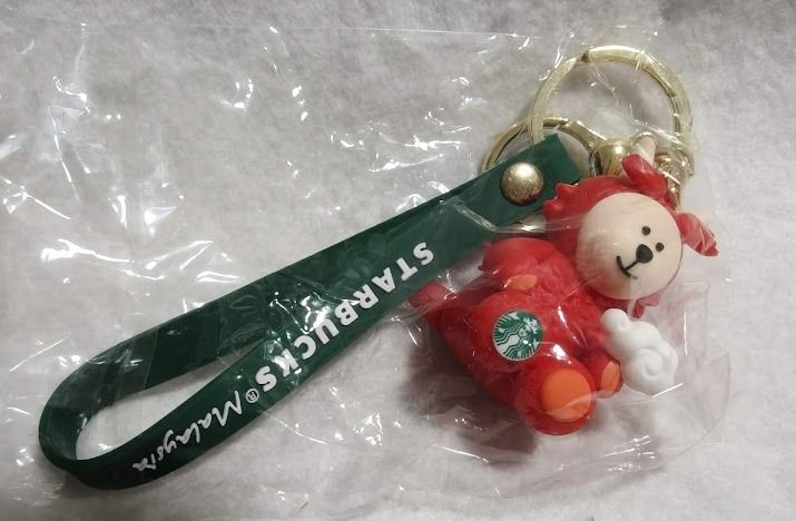 Starbucks Malaysia Year of the Dragon Bearista Keychain (Category: Plushies & Soft Toys) located in Singapore. Submitted by ageless_unicorn (Listing ID 1443870109, Image 1). Description: - Cute Starbucks Malaysia Year of the Dragon keychain - Features the red Dragon Bearista character - Green strap with 'Starbucks Malaysia' text - Comes with a gold keyring - Ideal for attaching to bags or keys - A collectible Starbucks item - 2 for $15.