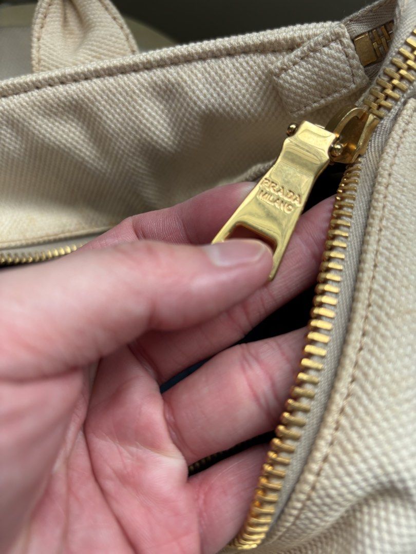 Prada Canvas bucket Tote Bag (Category: Bags & Wallets) located in Singapore. Submitted by forabargain (Listing ID 1444880004, Image 5). Description: - Authentic Prada cream canvas tote bag - Iconic Prada Milano triangle logo - Gold-tone zipper closure - Interior plaid lining with zippered pocket - Sturdy handles - Perfect for everyday use Selling as it is - not for fussy buyers..