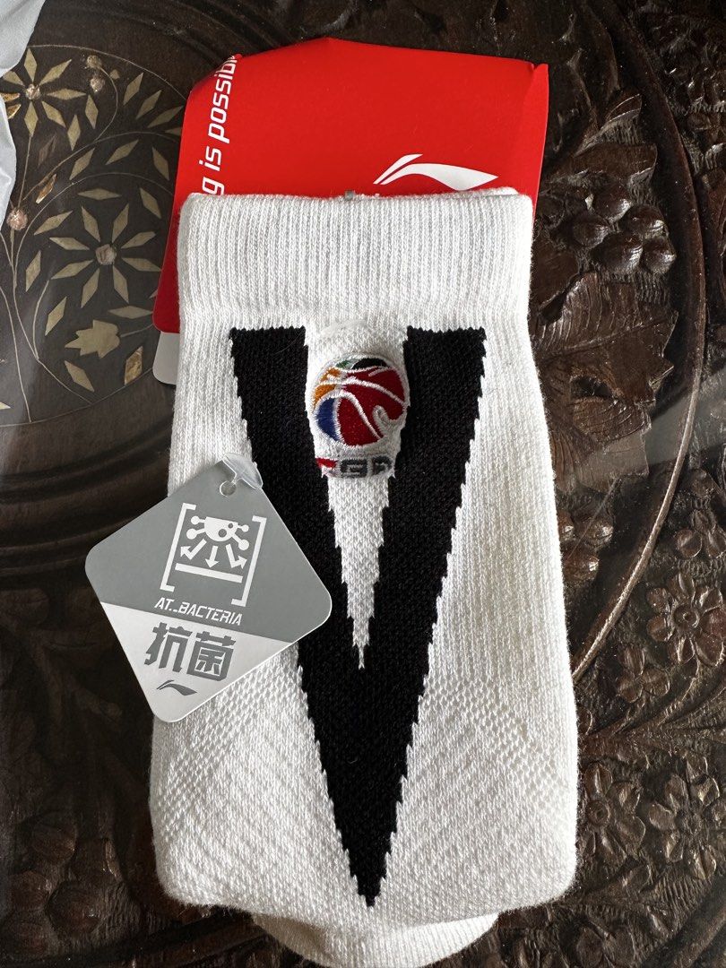 Li-Ning Basketball Socks at.bacteria White (Category: Socks) located in Singapore. Submitted by crystallee1357 (Listing ID 1446061341, Image 1). Description: - Brand: Li-Ning - Color: White - Design: Large black 'V' with basketball logo - Feature: Antibacterial (AT.BACTERIA tag) - Usage: Suitable for sports and everyday wear - Condition: Brand new, in original packaging.