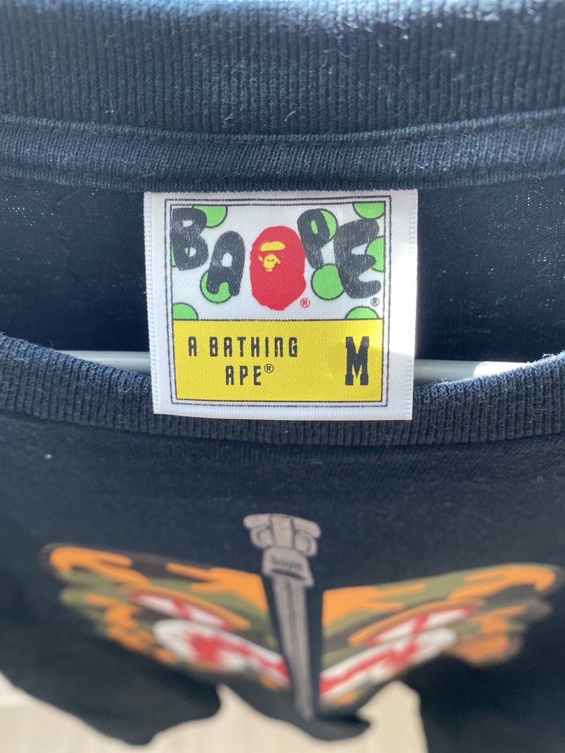 A Bathing Ape BAPE Tee (Category: Tshirts & Polo Shirts) located in Singapore. Submitted by joheun1616 (Listing ID 1446230581, Image 2). Description: 1 for $20, 2 for $35 BOTH wore 2 to 3 times only. - Black A Bathing Ape (BAPE) T-shirt x 2 - Size: Medium (M) - 1 x Front features iconic tiger camo with a zip graphic and back displays a tiger graphic and text - 1 x Front and Back features blue camo BAPE ape design - Small BAPE tag detail on the sl