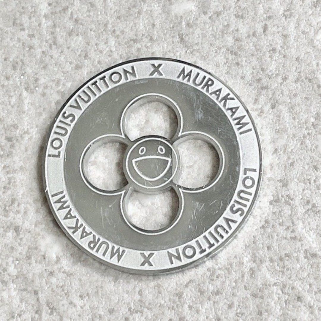 Louis Vuitton x Murakami Flower Charm Coin Token (Category: Accessories) located in Singapore. Submitted by sans57 (Listing ID 1442886872, Image 1). Description: Louis Vuitton x Murakami charm. Features the iconic smiling flower design Made of metal with engraved branding. Great for adding to bags or keychains. A collectible piece from the collaboration Rare! Only available for those who made purchase of LV Murakami items during limited pop-up pe