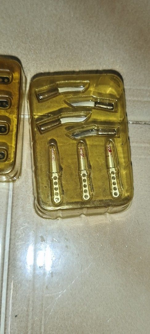 Dam toys 1/6 Miniature Knives Set in Display Case (Category: Action & Battle Toys) located in Singapore. Submitted by crayon-elephant (Listing ID 1448007632, Image 3). Description: - Set of 2 display cases - Total of 7 miniature knives - All knives are gold-colored with intricate details - One case: 4 smaller knives - Second case: 3 larger knives - Ideal for collectors or display purposes.