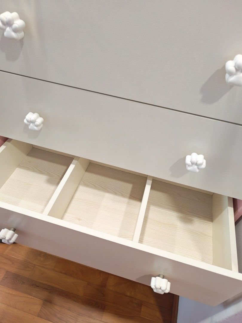 Pink Trim 5-Drawer Dresser with Paw Print Knobs (Category: Shelves, Cabinets & Racks) located in Singapore. Submitted by hsfinancing (Listing ID 1457771996, Image 2). Description: - Adorable dresser with charming pink trim. - Features 5 spacious drawers. - Each drawer is adorned with a cute white paw print knob. - Drawer interiors include convenient dividers. - Ideal for a child's bedroom or nursery. - Approximate dimensions: [height]cm (H) x [wi